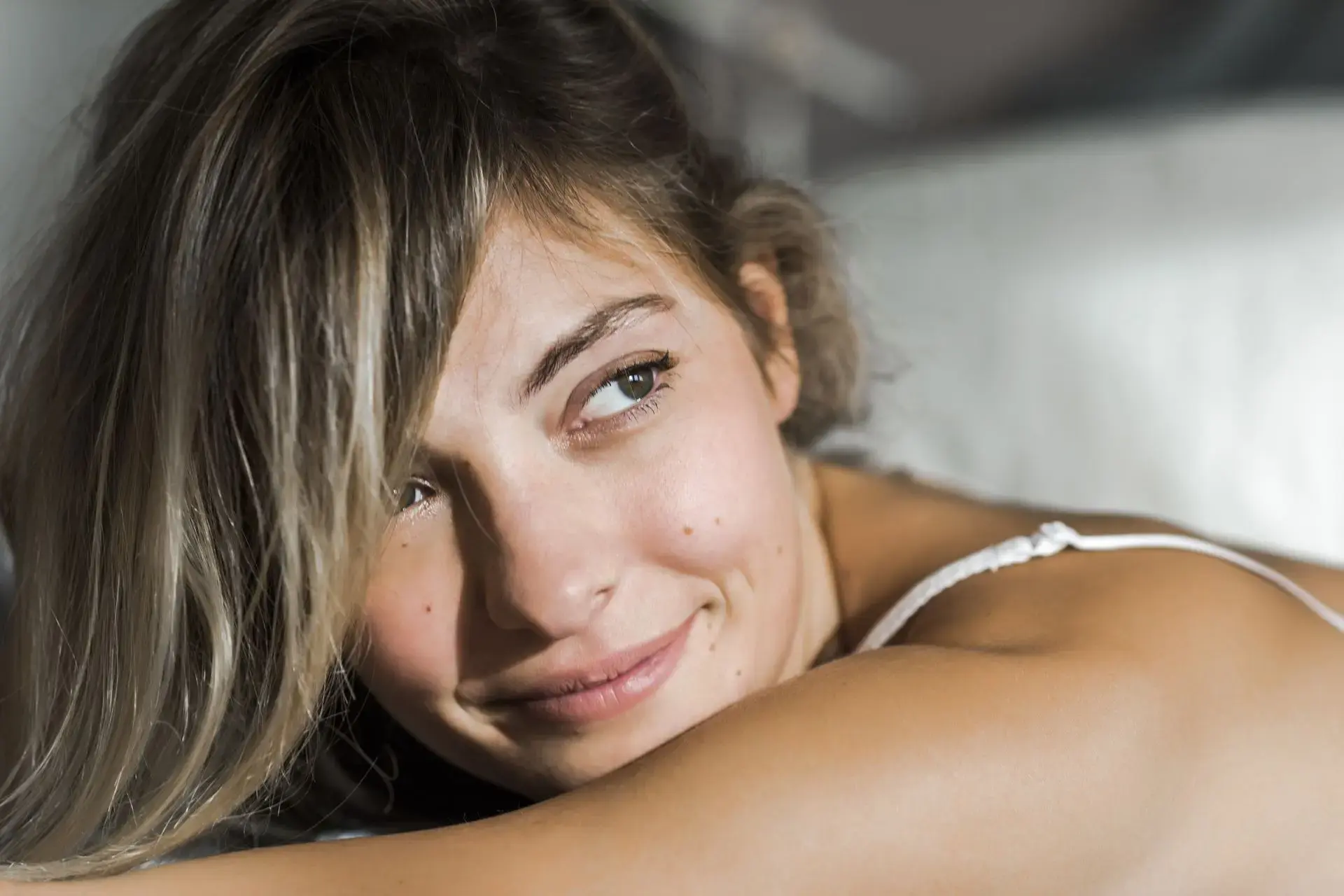 Femme allongée souriant tendrement, tête sur son bras