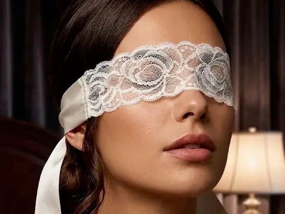 Bandeau en dentelle blanche IntimeCharme, noué sur les yeux par son ruban de satin